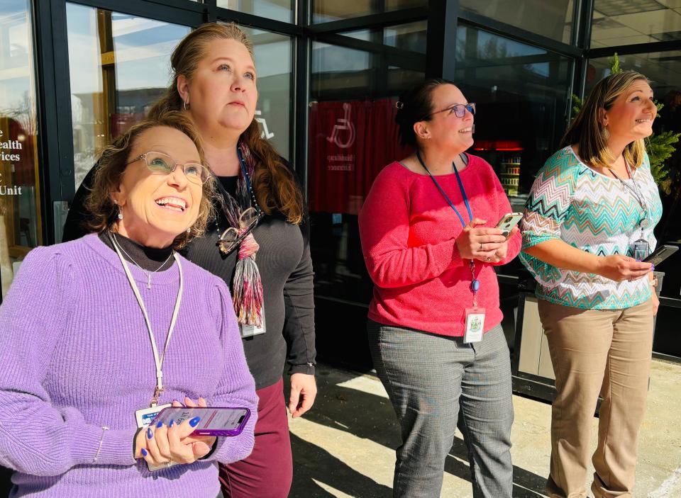 Debbie Bernier, left, Sheri Lietz, Cassandra Veilleux, and Candice Colman, all of the Department of Health and Human Services offices in Sanford, Maine, watch the eclipse from the entrance of Main Street Marketplace on Monday, April 8, 2024.