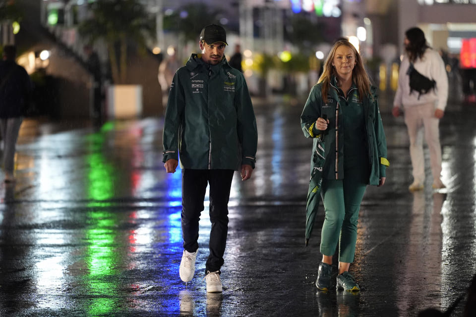 Aston Martin driver Lance Stroll, left, of Canada, walks in the rain to a media interview ahead of the Formula One Las Vegas Grand Prix auto race, Wednesday, Nov. 15, 2023, in Las Vegas. (AP Photo/Nick Didlick)