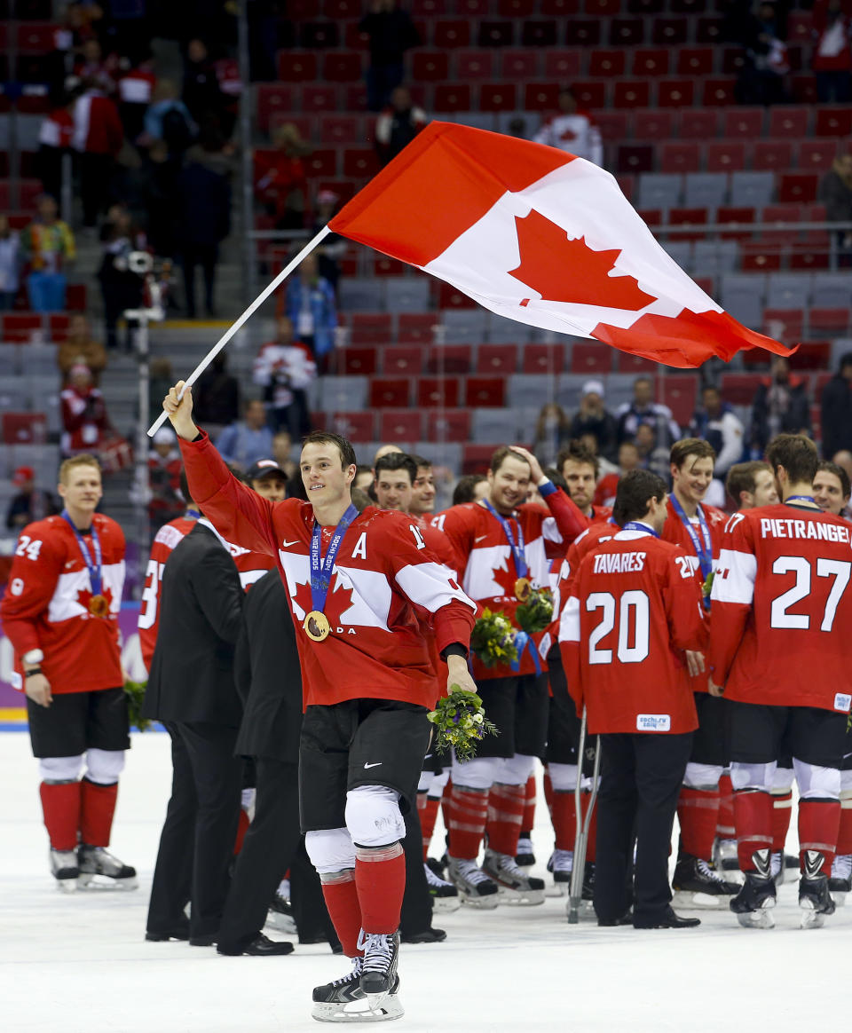 Canada forward Jonathan Toews waves the Canadian flag after Canada beat Sweden 3-0 in the men's gold medal ice hockey game at the 2014 Winter Olympics, Sunday, Feb. 23, 2014, in Sochi, Russia. (AP Photo/Matt Slocum)