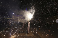 A Pakistani Hindu hold a firework at a ceremony to celebrate Diwali, the festival of lights, at Swami Narayan temple in Karachi, Pakistan, Saturday, Nov. 14, 2020. The Hindu festival of lights, Diwali celebrates the spiritual victory of light over darkness. (AP Photo/Fareed Khan)