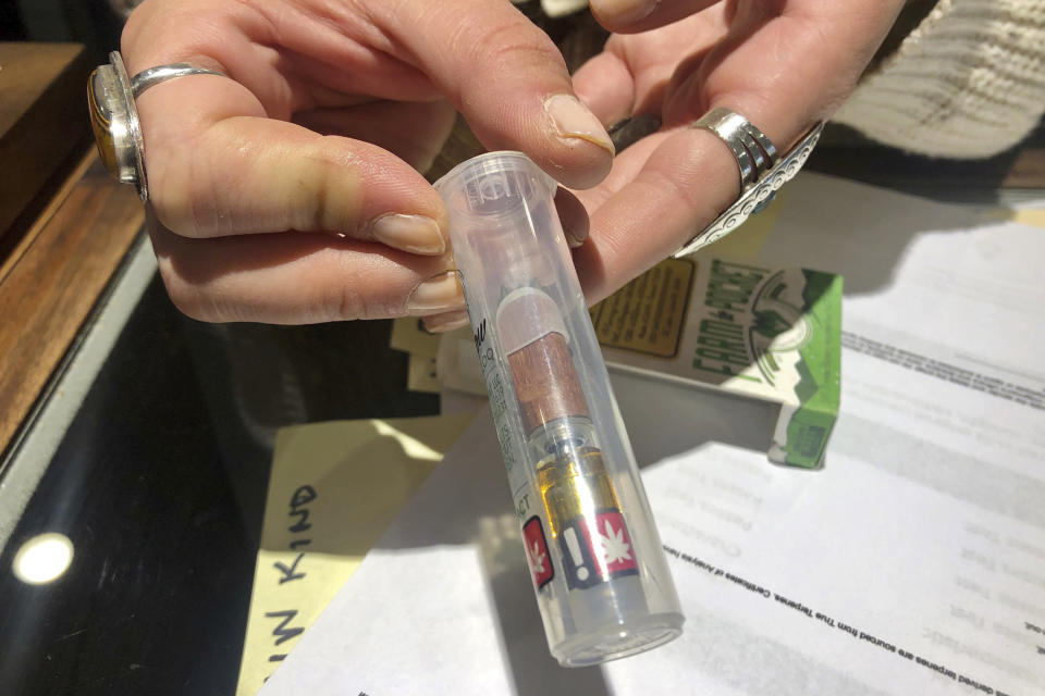 In this photo taken Sept. 20, 2019, Cameron Moore, general manager of Bridge City Collective in Portland, Ore., holds a vape cartridge that's on sale at the dispensary. The company had a 31% drop in sales of vape cartridges that hold the oil that vaporizes when heated. Vaping products are taking a hit as health experts scramble to determine what’s causing a mysterious lung disease. (AP Photo/Gillian Flaccus)