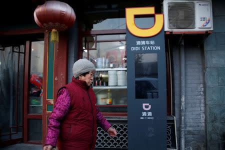 FILE PHOTO: A woman walks past a sign of station for Didi Chuxing in Beijing, China January 2, 2019. REUTERS/Jason Lee/File Photo