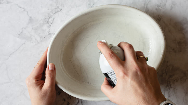 spraying casserole with cooking spray