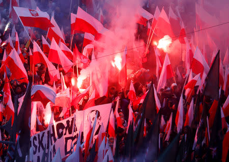 People carry Polish flags and flares during a march marking the 100th anniversary of Polish independence in Warsaw, Poland November 11, 2018. REUTERS/Kacper Pempel