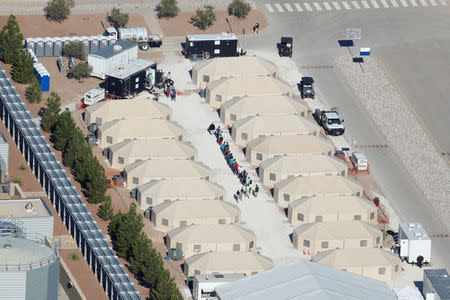 Immigrant children now housed in a tent encampment under the new "zero tolerance" policy by the Trump administration are shown walking in single file at the facility near the Mexican border in Tornillo, Texas, U.S. June 19, 2018. REUTERS/Mike Blake