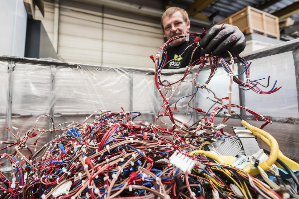 In this photo taken on July 13, 2018, a worker puts wiring from electrical components into a bin at the Out Of Use company warehouse in Beringen, Belgium. Out Of Use dismantles computer, office and other equipment and recuperates an average of around 90 percent of the raw materials from electronic waste. (AP Photo/Geert Vanden Wijngaert)