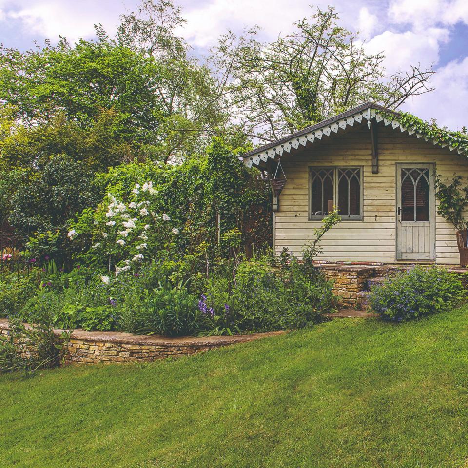 A garden with a summer house and green lawn