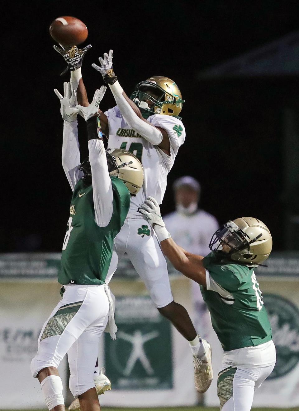 Youngstown Ursuline wide receiver Jakylan Irving, center, hauls in a pass over STVM defensive backs JaeSon Anderson, left, and Kai White, right, during the first half of a high school football game, Friday, Oct. 1, 2021, in Akron, Ohio.