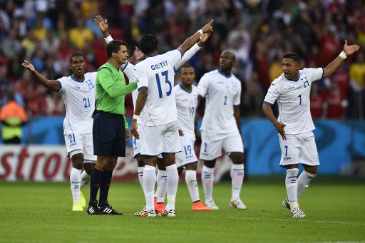 Los futbolistas de Honduras le reclaman la validación de un gol de Francia al árbitro brasileño Sandro Ricci, en partido del Grupo E del Mundial-2014, el 15 de junio en el estadio Beira Rio de Porto Alegre (AFP | Rodrigo Buendía)