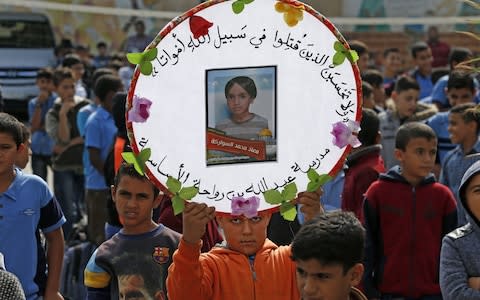 Palestinian pupils hold a commemorative picture of their late classmate Moaz Abu Malhous at his school in Deir al-Balah town in central Gaza Strip, on November 16, 2019, two days after he was reportedly killed in an Israeli strike. - Credit: AFP