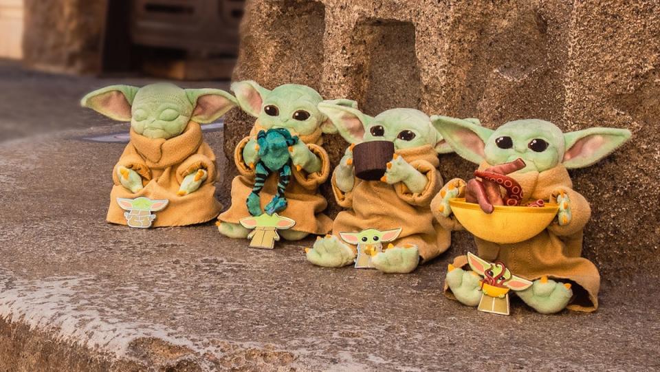 Four plush dolls of Baby Yoda from The Mandalorian, each with a matching enamel pin