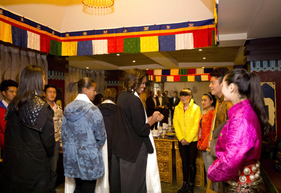 U.S. first lady Michelle Obama, center, her daughters Sasha, second left in front, Malia, front left, are greeted by Tibetan students as they arrive at a Tibetan restaurant for lunch in Chengdu in southwest China's Sichuan province Wednesday, March 26, 2014. (AP Photo/Andy Wong)