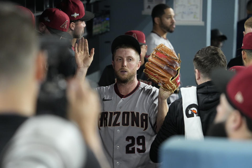 Arizona Diamondbacks starting pitcher Merrill Kelly celebrates with teammates in the dugout after exiting during the seventh inning in Game 1 of a baseball NL Division Series against the Los Angeles Dodgers, Saturday, Oct. 7, 2023, in Los Angeles. (AP Photo/Mark J. Terrill)