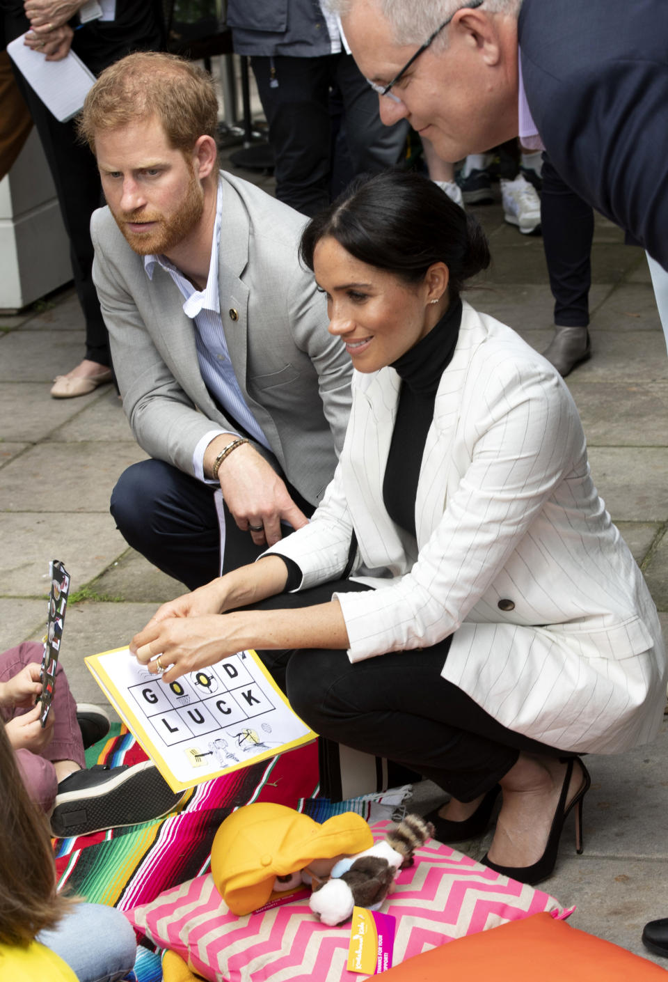 Britain's Prince Harry, left, and his wife Meghan, the Duchess Sussex talk with school children as they attend a lunchtime reception hosted by Prime Minister Scott Morrison with Invictus Games competitors, their family and friends in the city's central parkland in Sydney on Sunday, Oct. 21, 2018. (Paul Edwards/Pool Photo via AP)