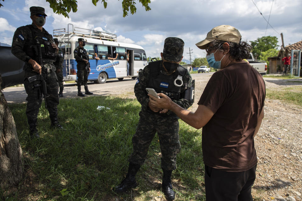 Friar Leopoldo Serrano, right, shows soldiers images he made with his cellphone of a suspicious truck seen near the entrance of his mission, in Mission San Francisco de Asis, Honduras, Friday, June 25, 2021. Serrano’s message is not widely popular. He has sought protection for his mission, which is routinely observed by men passing by in oversized SUVs with tinted windows. (AP Photo/Rodrigo Abd)