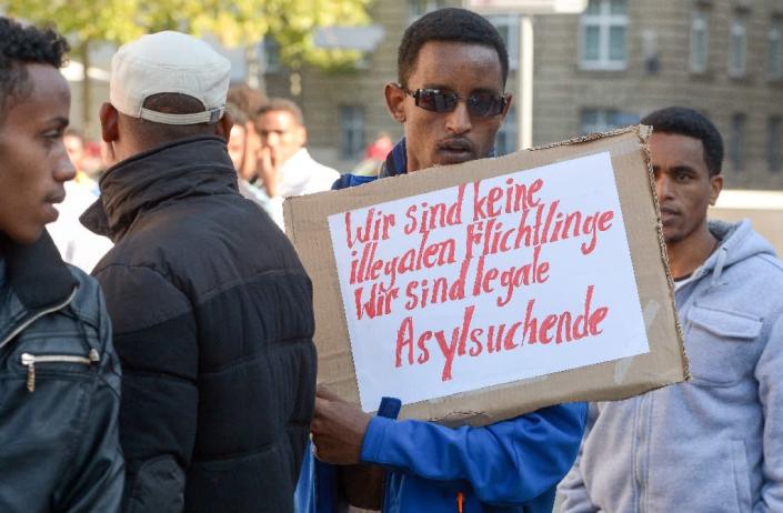 A refugee from Eritrea holds a poster reading "We are not illegal refugees - we are legal asylum-seekers" during a demonstration against the German procedure for granting asylum on October 2, 2015 in Erfurt, eastern Germany (AFP Photo/Peter Endig)