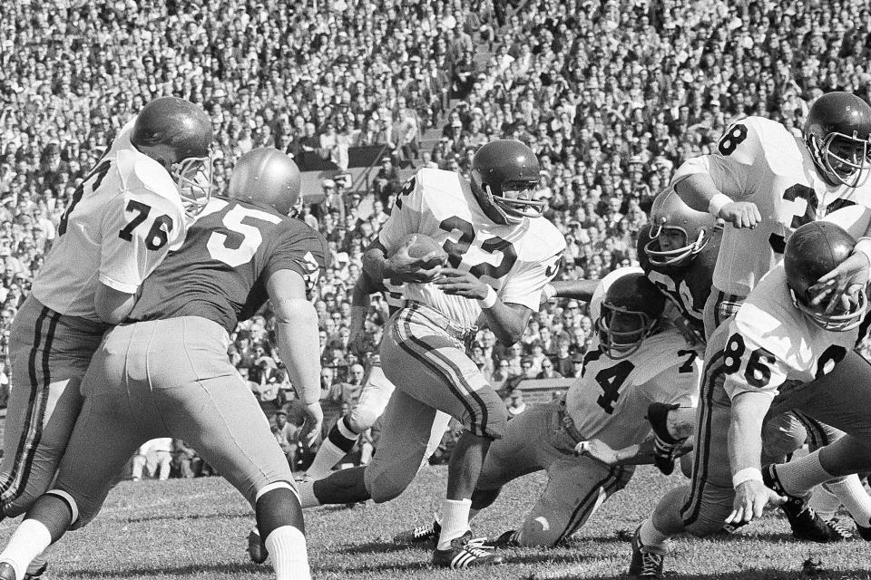 ARCHIVO - El corredor de la Universidad del Sur de California O.J. Simpson (32) corre contra Notre Dame en la primera mitad de un partido de fútbol americano universitario de la NCAA en South Bend, Indiana, 14 de octubre de 1967. En la jugada están Bob Miller (86), Mike Taylor (74) y Dan Scott (38) de USC O.J. Simpson, el laureado astro del fútbol americano y actor de Hollywood que fue absuelto de los cargos de doble asesinato de su exesposa y su amigo, pero luego declarado responsable en un juicio civil aparte, ha fallecido. Tenía 76 años. (Foto AP/archivo)