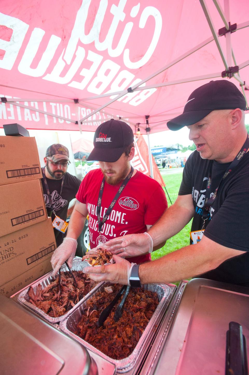 City Barbecue regional catering director Jeremiah Ruxer, left, looks on as Ryan Thomas, a catering associate, center, and Jack Gordon, City Barbecue executive director, fill an order of pork atop macaroni and cheese at the Blues, Brews and BBQ Festival in Louisville Water Tower Park.
June 21, 2019