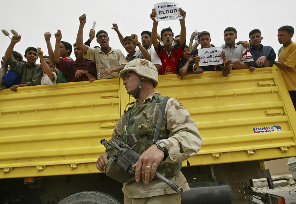 FILE - Iraqi mourners, leading a procession with coffins carrying the dead, protest in front of American soldiers guarding a site where an American ammunition dump exploded and killed at least six Saturday April 26, 2003. (AP Photo/David Guttenfelder, File)