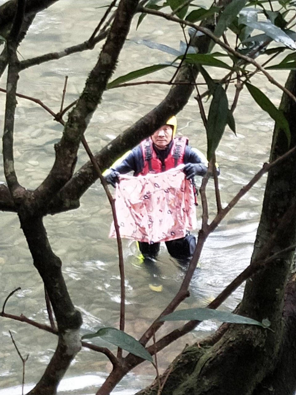 新北市虎豹潭落水意外已釀4死，尚有15歲陳姓少女和8歲劉姓女童失蹤，搜救人員18日上午10時28分在落水點附近找到雨衣和鞋子，經家人確認後為劉姓女童所有。（中央社／讀者提供）