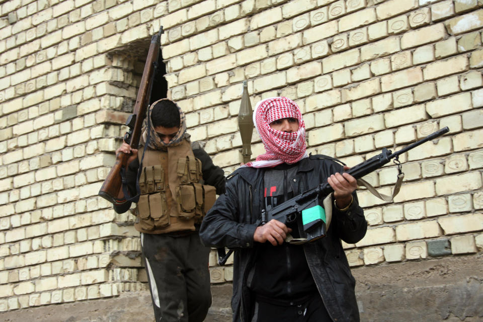 In this Sunday, Jan. 5, 2014 picture, gunmen patrol during clashes with Iraqi security forces in Fallujah, Iraq. Clashes continued late Sunday and early morning Monday between al-Qaida and Iraqi troops on the main highway that links the capital, Baghdad, to neighboring Syria and Jordan. Al-Qaida fighters and allied tribes are still controlling the center of the city where they are deployed in streets and around government buildings. (AP Photo)