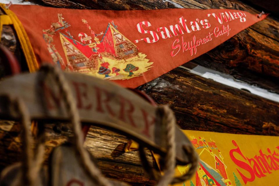 Pennants hung on a log wall, reading "Santa's Village Skyforest Calif."