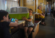 A girl holds a crate with her pet cat inside while a boy plays on a phone inside an evacuation train waiting for departure after they where evacuated from the war hit area in Pokrovsk in eastern Ukraine, Saturday June 11, 2022. (AP Photo/Efrem Lukatsky)