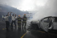 Firefighters and police work together to douse with water a vehicle set on fire by a group of veterans demanding that a law be passed that compensates them for having served during the country's civil war, outside the Congress building in Guatemala City, Tuesday, Oct. 19, 2021. (AP Photo/Moises Castillo)