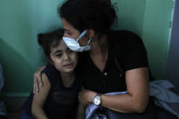 A teacher hugs a student who is afraid of the sounds from nearby armed clashes, at a school, at the Christian neighborhood of Ain el-Remaneh, in Beirut, Lebanon, Thursday, Oct. 14, 2021. Armed clashes broke out in Beirut Thursday during the protest against the lead judge investigating last year's massive blast in the city's port, as tensions over the domestic probe boiled over. (AP Photo/Hussein Malla)