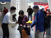 Health officials check passengers at the Kuala Lumpur International Airport in Sepang, Malaysia, Tuesday, Jan. 21, 2020. Countries both in the Asia-Pacific and elsewhere have initiated body temperature checks at airports, railway stations and along highways in hopes of catching those at risk of carrying a new coronavirus that has sickened more than 200 people in China. (AP Photo/Vincent Thian)