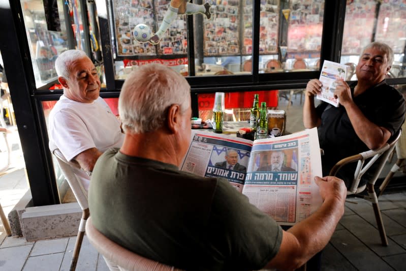 An Israeli man reads a local daily newspaper as he sits in a coffee shop in Ashkelon