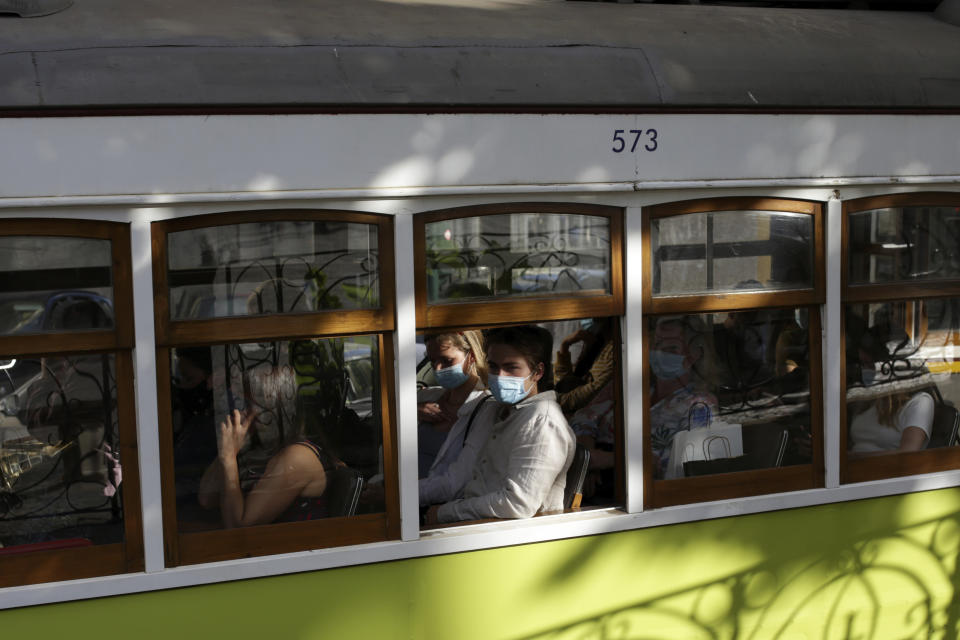 People wearing face masks ride a tram in Lisbon, Friday, June 4, 2021. Britain said Thursday that it is removing Portugal from its list of COVID-safe travel destinations, meaning thousands of U.K. residents currently on vacation there face the prospect of 10 days' quarantine on return. (AP Photo/Armando Franca)