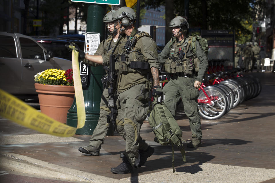 Montgomery police officers in tactical gear exit a parking garage where a police officer was shot, in downtown Silver Spring, Md., Monday, Oct. 14, 2019. Police in Montgomery County, Maryland, said they were searching for at least one person after an officer was found shot in a parking garage in downtown Silver Spring on Monday. (AP Photo/Jose Luis Magana)