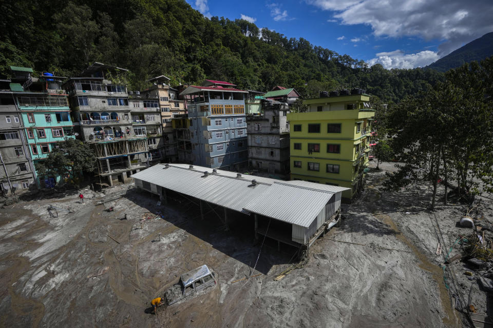 A man digs as he tries to recover a vehicle submerged in mud in the flood affected area along the Teesta river in Rongpo, east Sikkim, India, Sunday, Oct. 8. 2023. Rescuers continued to dig through slushy debris and ice-cold water in a hunt for survivors after a glacial lake burst through a dam in India’s Himalayan northeast, shortly after midnight Wednesday, washing away houses and bridges and forcing thousands to flee. (AP Photo/Anupam Nath)