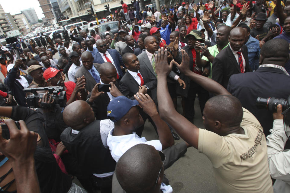 Zimbabwe top opposition leader Nelson Chamisa, center, arrives to deliver his speech at the party headquarters in Harare, Wednesday, Nov. 20, 2019. Zimbabwean police with riot gear fired tear gas and struck people who had gathered at the opposition party headquarters to hear a speech by the main opposition leader Nelson Chamisa who still disputes his narrow loss to Zimbabwean President Emmerson Mnangagwa. (AP Photo/Tsvangirayi Mukwazhi)