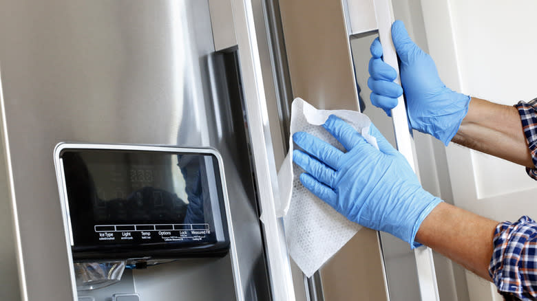 gloved hands cleaning fridge