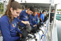 University of Miami's Rosenstiel School of Marine & Atmospheric Science students Simone Nix, 22, left, Grace Benyon, 22, center, and Jack Benham, 21, prepare their dive gear before a night dive to check on coral spawning, Monday, Aug. 15, 2022, in Key Biscayne, Fla. A group of students and scientists were hoping to observe the coral spawn and collect their eggs and sperm, called gametes, to take back to the lab to hopefully fertilize and create new coral that will later be transplanted to help repopulate part of the Florida Reef Tract, but the coral did not cooperate that night. (AP Photo/Wilfredo Lee)