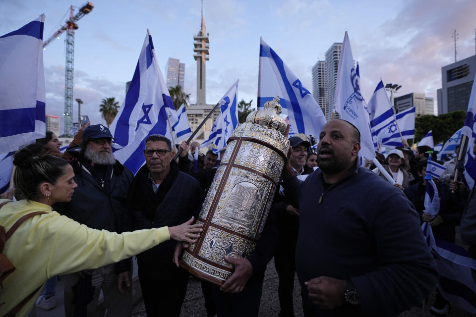 FILE - Right-wing Israelis march with the Torah at a rally in support of Prime Minister Benjamin Netanyahu's government plans to overhaul the judicial system, in Tel Aviv, Israel, Thursday, March 30, 2023. As Israel turns 75, it has much to celebrate. But instead of feting its accomplishments as a regional and economic powerhouse, the nation founded as a home for the world's Jews in the wake of the Holocaust finds itself under threat -- not by foreign enemies but by bitter internal divisions. (AP Photo/Ariel Schalit, File)