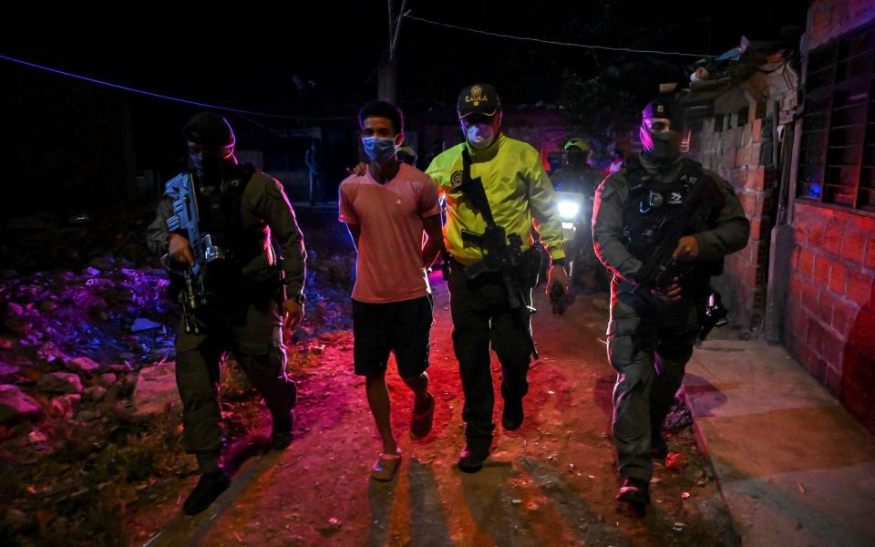 Colombian police of the GOES Special Operations Group escort an arrested man, on July 29, 2020 in Cali, Colombia, during an operation against criminal gangs and drug traffickers in the Aguablanca district, one of the most dangerous areas of the city