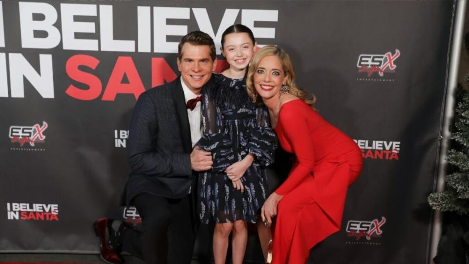 John Ducey, Violet McGraw and Christina Moore celebrate Christmas early at the premiere of “I Believe in Santa” at Warner Bros. Studios in Burbank. (Helen Rezvan)