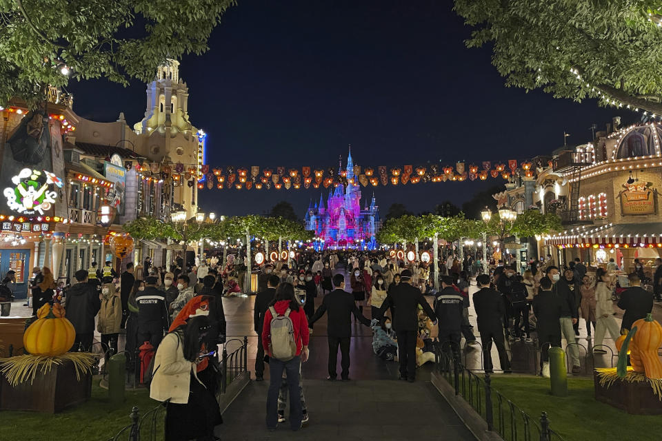 In this photo released by MiaoMiao, security guards hold hands to control the crowds at the main entrance of the Disney Resort theme park in Shanghai, China on Tuesday, Nov. 1, 2022. Visitors to Shanghai Disneyland were temporarily blocked from leaving as part of virus testing that extended to more than 400,000 people, the city government announced Tuesday. (MiaoMiao via AP)