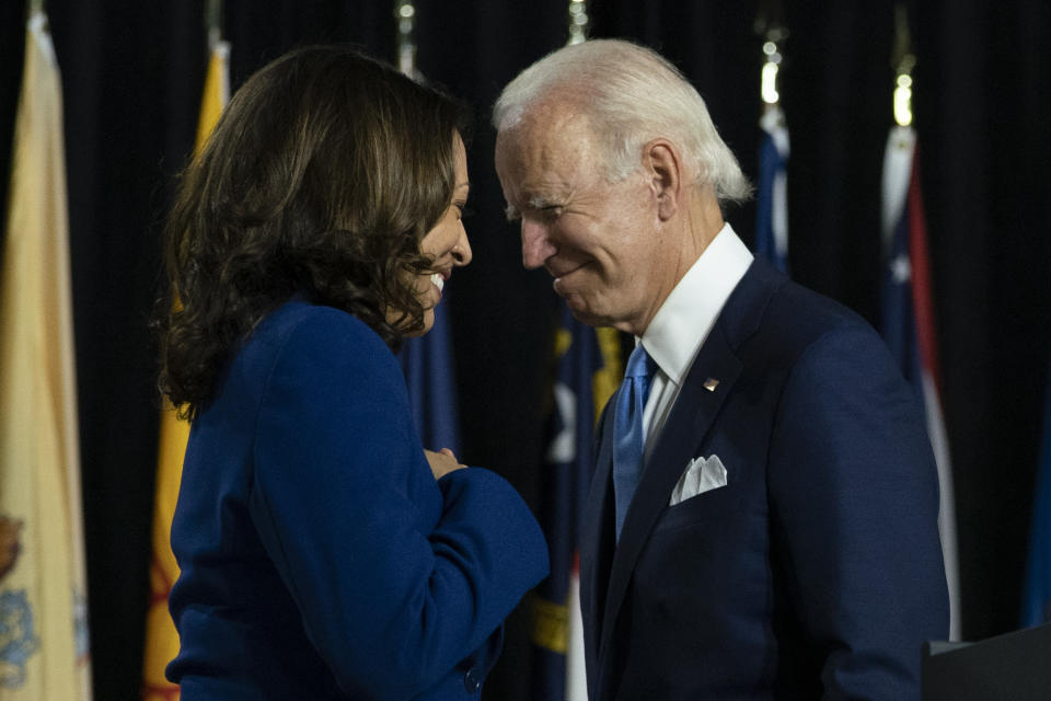 FILE - In this Aug. 12, 2020, file photo, Democratic presidential candidate former Vice President Joe Biden and his running mate Sen. Kamala Harris, D-Calif., pass each other as Harris moves to the podium to speak during a campaign event at Alexis Dupont High School in Wilmington, Del. A tough road lies ahead for Biden who will need to chart a path forward to unite a bitterly divided nation and address America’s fraught history of racism that manifested this year through the convergence of three national crises. (AP Photo/Carolyn Kaster, File)