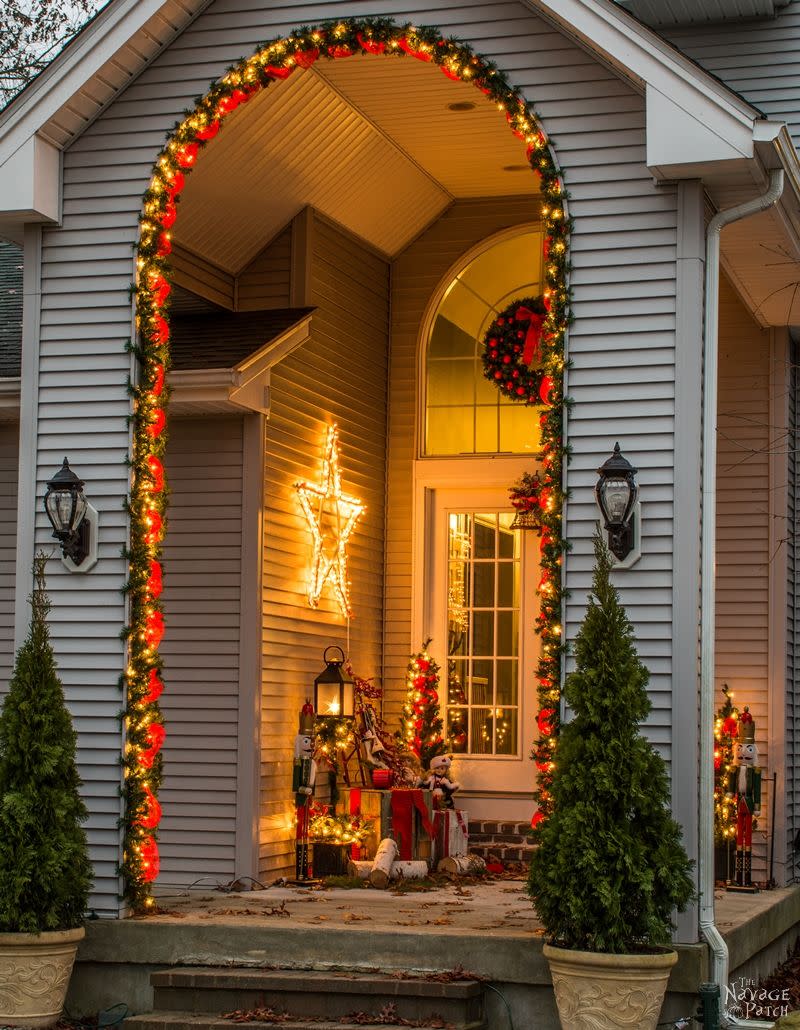 green garland with red ribbon and twinkle lights around an archway (The Navage Patch)