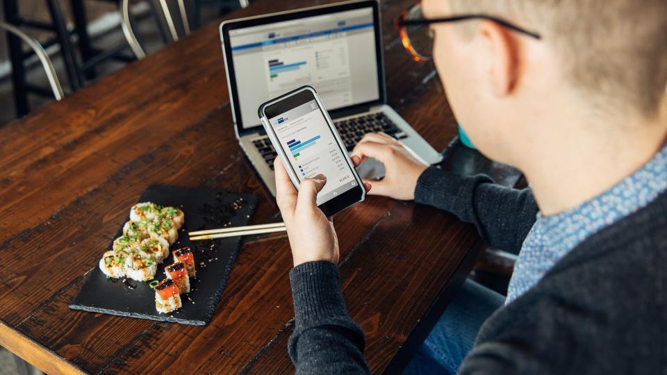 A man of the Millennial Generation is looking at his financial statement while eating lunch at a local sushi restaurant.