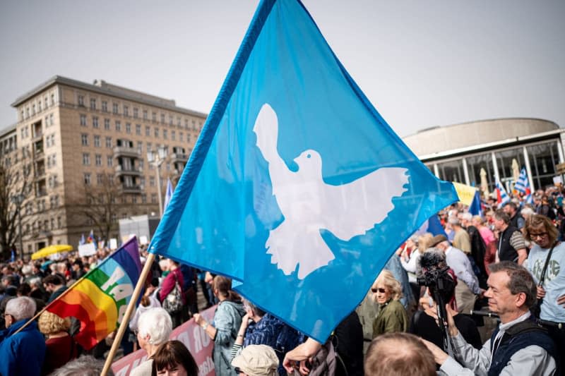 A flag with a dove of peace can be seen at the traditional Easter march under the motto "Warlike - Never Again". Fabian Sommer/dpa