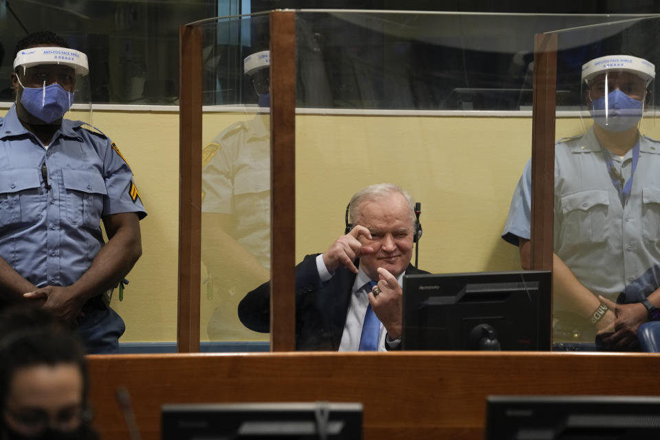 Former Bosnian Serb military chief Ratko Mladic imitates taking pictures as he sits the court room in The Hague, Netherlands, Tuesday, June 8, 2021, where the United Nations court delivers its verdict in the appeal of Mladic against his convictions for genocide and other crimes and his life sentence for masterminding atrocities throughout the Bosnian war. (AP Photo/Peter Dejong, Pool)