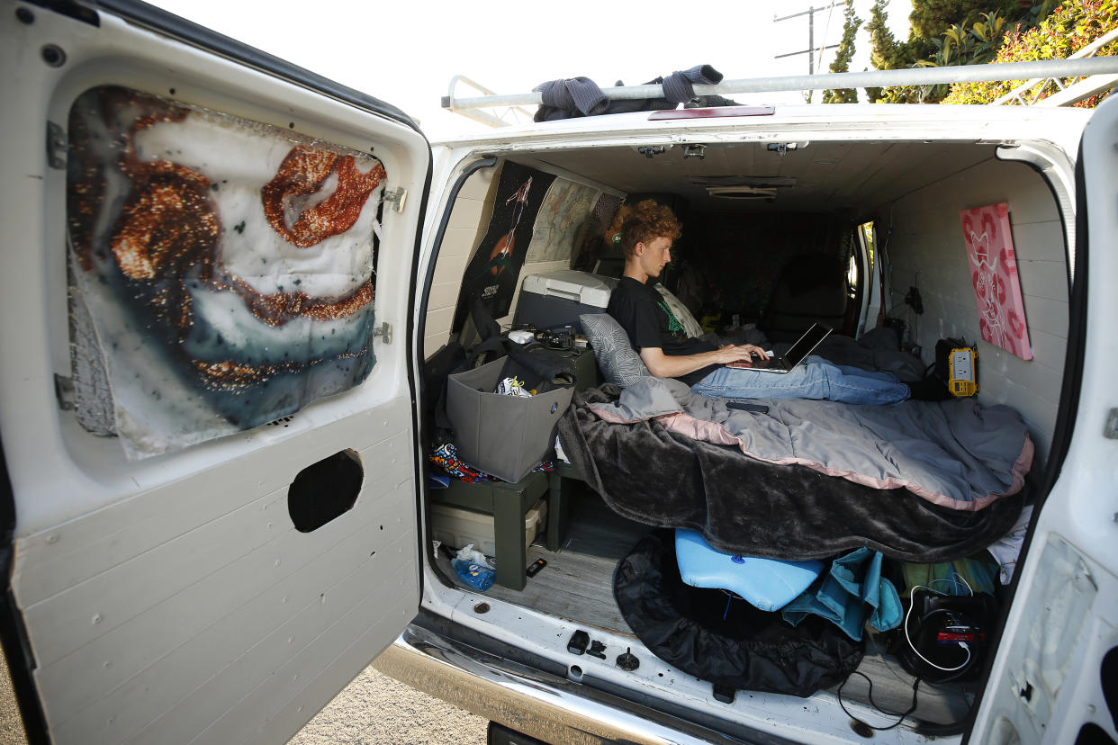 College student Kris Hotchkiss works on his laptop in a van.