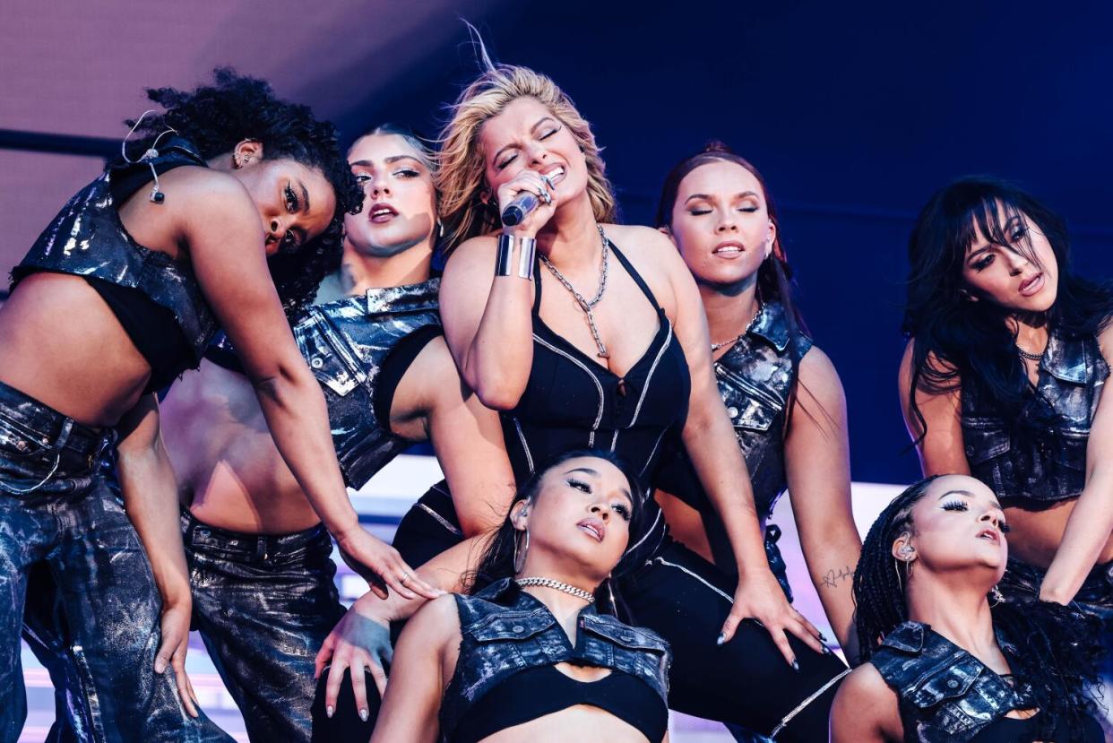 Bebe Rexha performs surrounded by dancer in shiny black outfits.