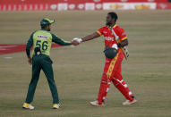 Pakistan's skipper Babar Azam, left, greets Zimbabwe's batsman Elton Chigumbura, who arrives to play his last match during their 3rd Twenty20 cricket match at the Pindi Cricket Stadium, in Rawalpindi, Pakistan, Tuesday, Nov.10, 2020. Chigumbura announced his retirement from international cricket. (AP Photo/Anjum Naveed)