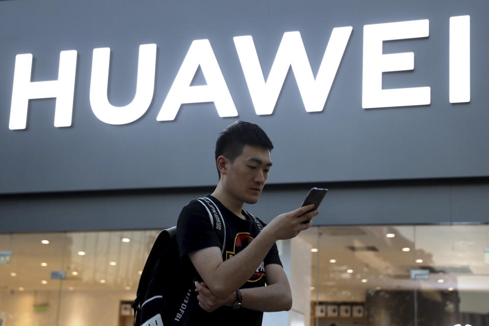 In this Monday, May 20, 2019, photo, a man uses his smartphone outside a Huawei store in Beijing. Chinese tech giant Huawei has filed a motion in U.S. court challenging the constitutionality of a law that limits its sales of telecom equipment. (AP Photo/Ng Han Guan)